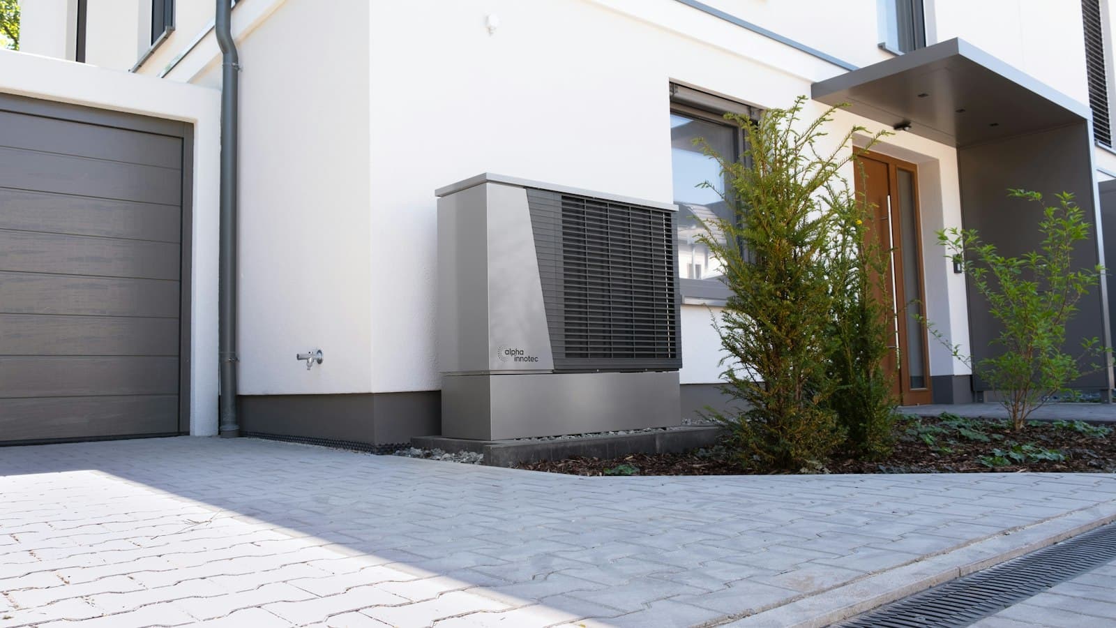 Modern heat pump outdoor unit installed at the front of a single-family home