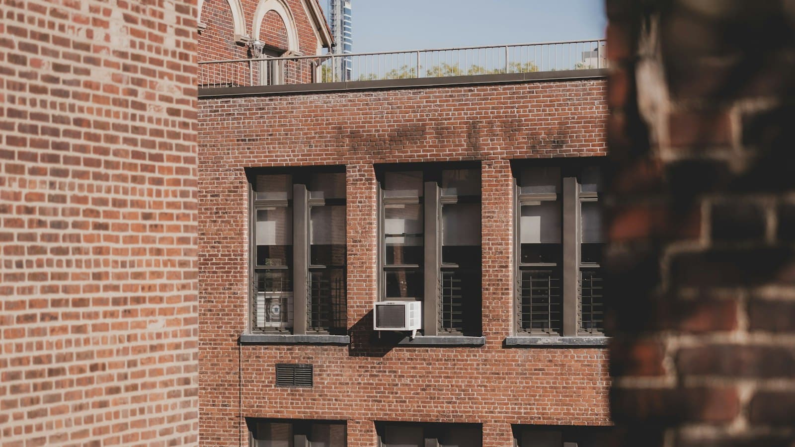 Window air conditioner in a brick New York apartment building on a hot, sunny day