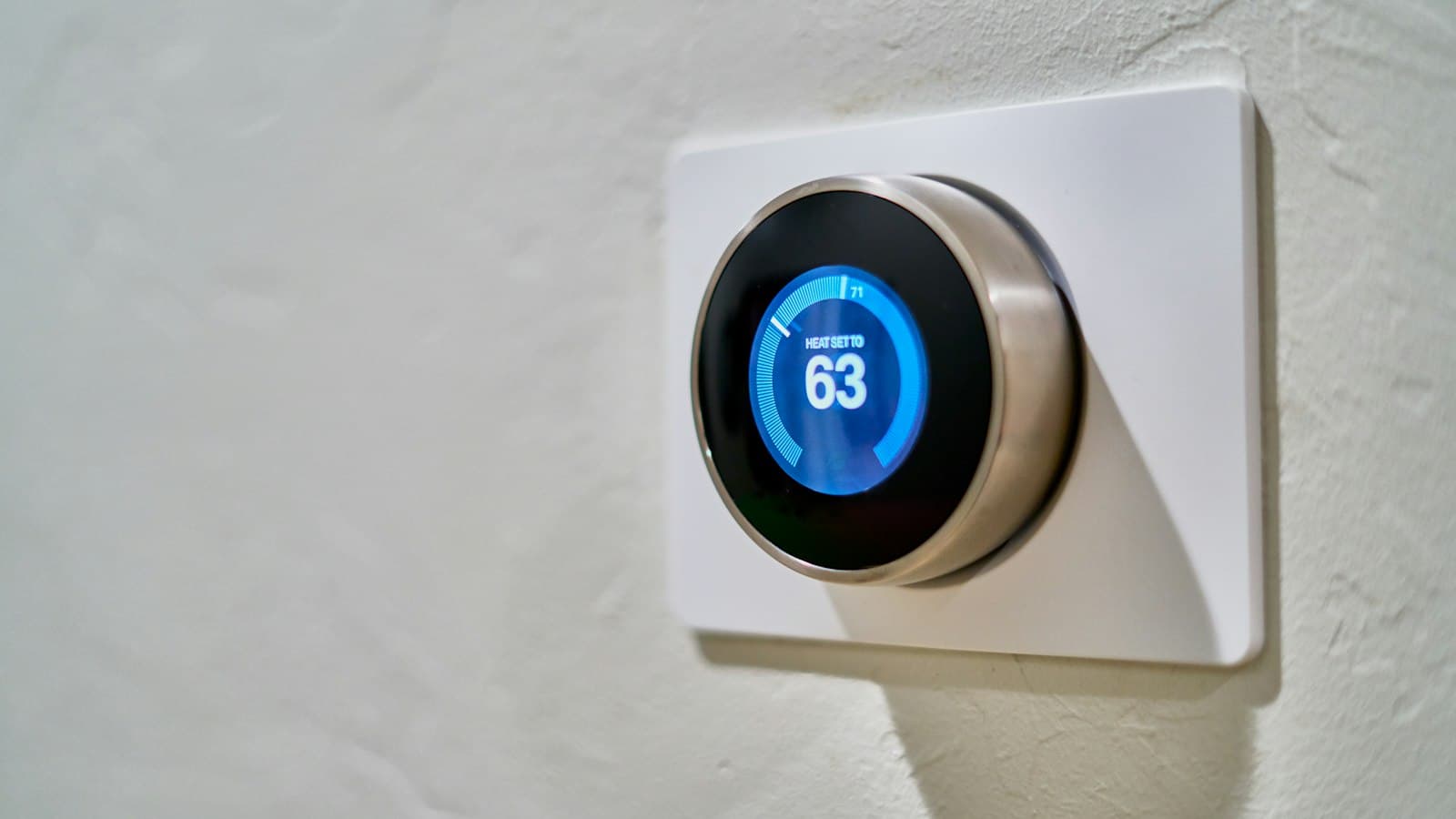 Round smart thermostat on a home wall — set it before the first cold snap, not during it